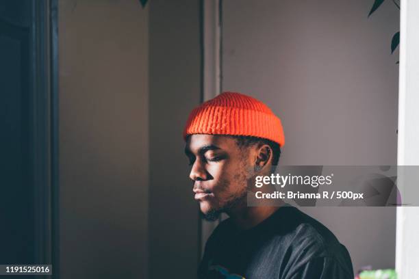 portrait of young man with eyes closed wearing red cap, toronto, canada - eyes closed stockfoto's en -beelden