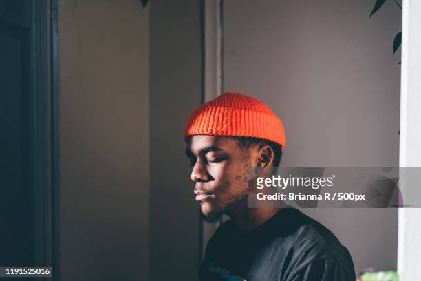 portrait of young man with eyes closed wearing red cap, toronto, canada - zen stock pictures, royalty-free photos & images