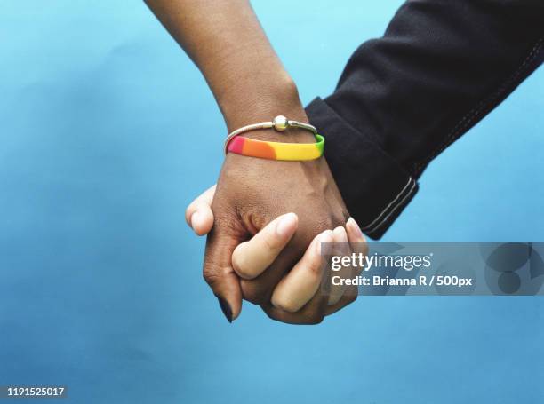 close-up of two hands holding against blue background, toronto, canada - union gay bildbanksfoton och bilder