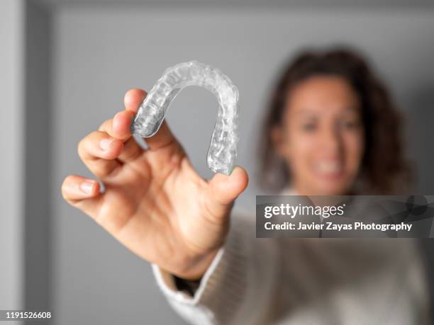 woman holding an invisible orthodontics - women in suspenders fotografías e imágenes de stock