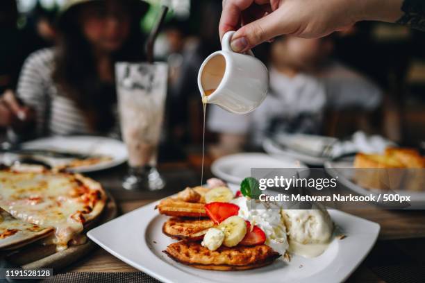person pouring syrup on dessert - maple syrup stock pictures, royalty-free photos & images