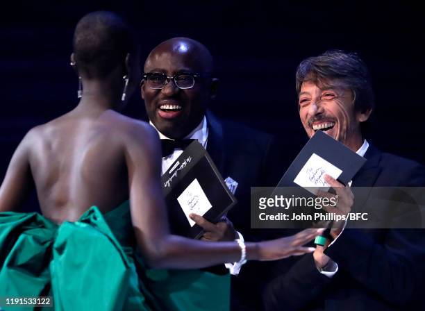 Adut Akech is presented with the Model of the Year Award by Edward Enninful and Pier Paolo Piccioli on stage during The Fashion Awards 2019 held at...