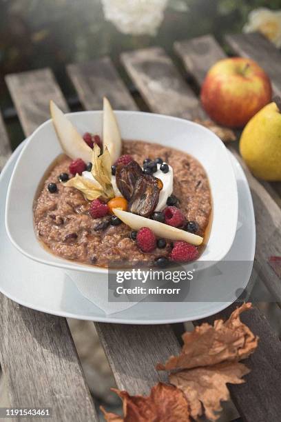 healthy homemade gluten free breakfast – buckwheat porridge with pecan nuts, blueberries, raspberries and dates on wooden background with autumn, fall atmosphere - buckwheat stock pictures, royalty-free photos & images