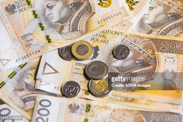 In this photo illustration polish zloty banknotes and coins seen displayed.