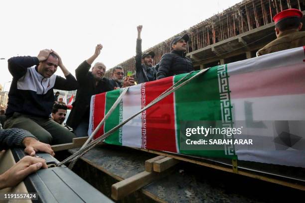 Iraqis mourn over a coffin during the funeral procession of Iraqi paramilitary chief Abu Mahdi al-Muhandis and Iranian military commander Qasem...