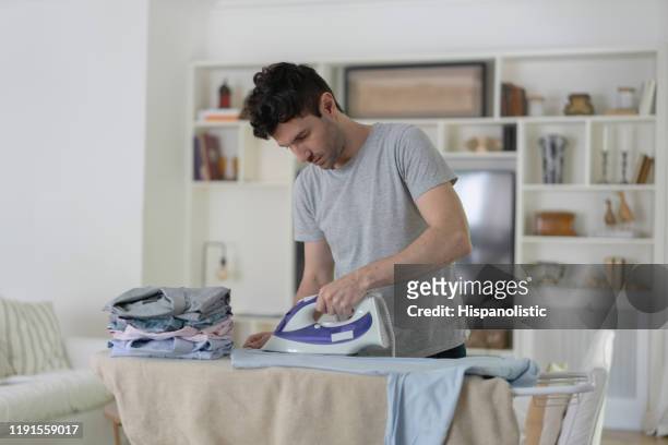 lateinamerikanische mann zu hause bügeln seinen knopf nach unten hemden - ironing stock-fotos und bilder