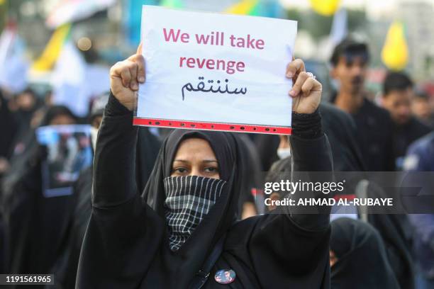 An Iraqi woman holds a placard during the funeral of Iranian military commander Qasem Soleimani, Iraqi paramilitary chief Abu Mahdi al-Muhandis and...