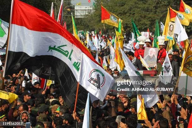 Mourners surround a car carrying the coffin of Iraqi paramilitary chief Abu Mahdi al-Muhandis during a funeral procession, for him and nine others,...