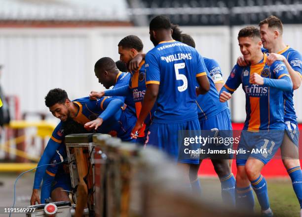 Sean Goss of Shrewsbury Town falls through the advertising boards as he celebrates with his team mates after scoring a goal to make it 1-1 during the...