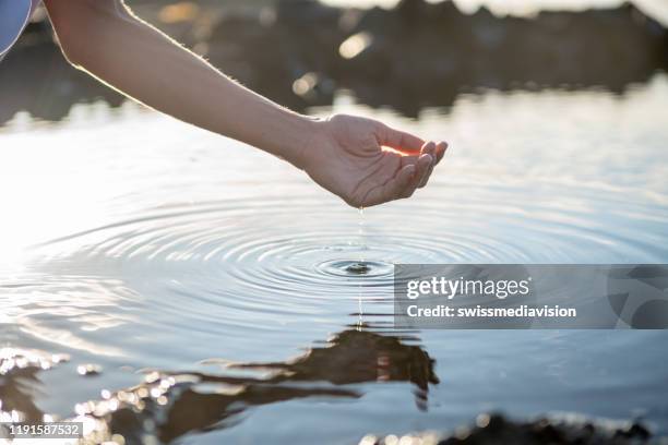 menschliche hand gezappt, um frisches wasser aus dem seeteich in felsen zu fangen - hand wasser stock-fotos und bilder