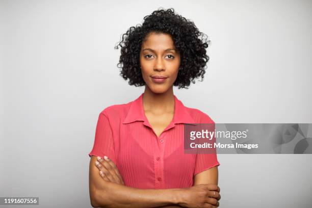 confident businesswoman with arms crossed - african american young woman portrait white background stock-fotos und bilder