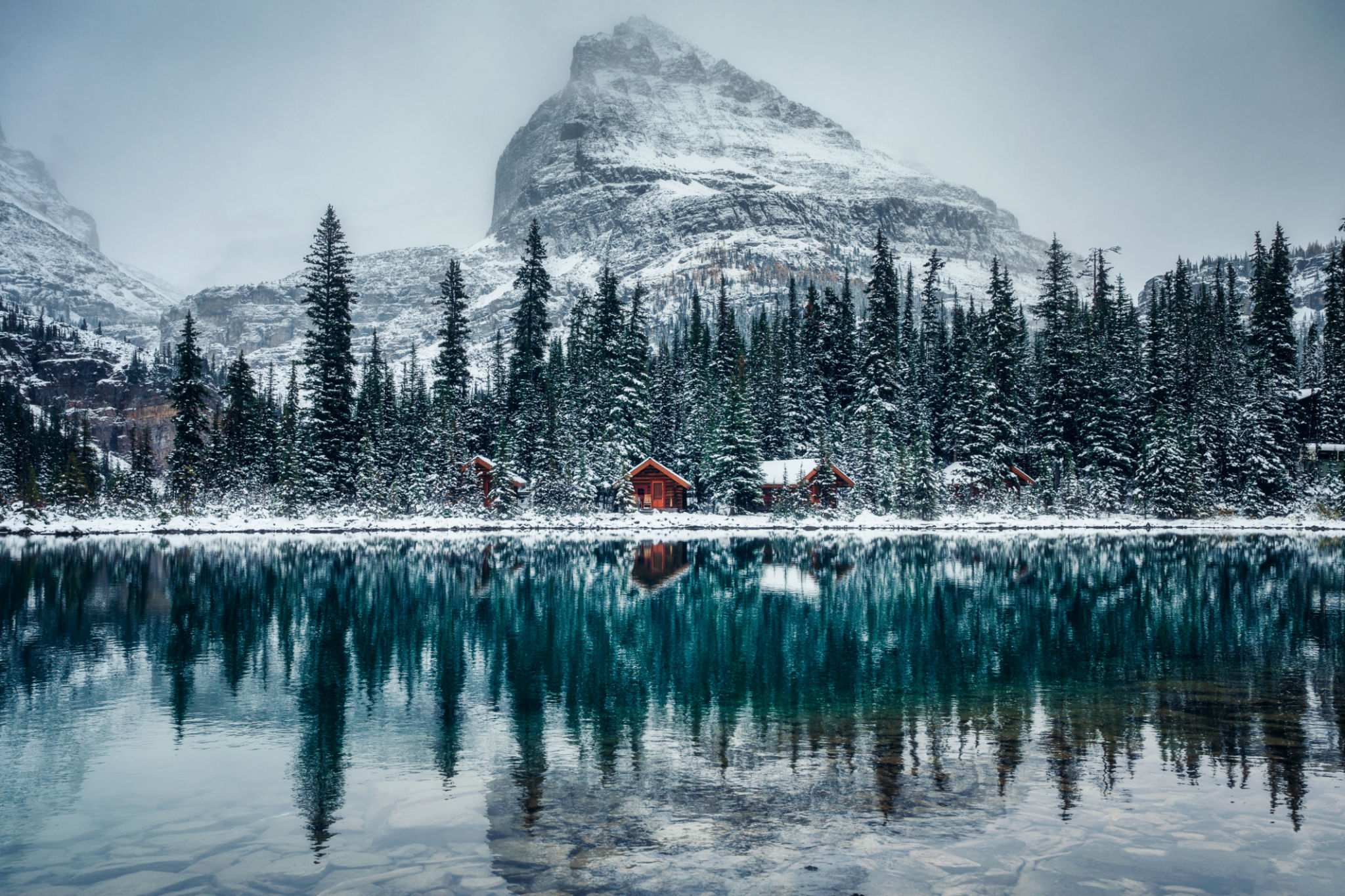 Wooden lodge in pine forest with heavy snow reflection on Lake O'hara at Yoho national park Wooden lodge in pine forest with heavy snow reflection on Lake O'hara at Yoho national park