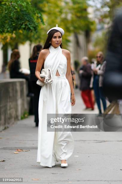 Guest wears a white beret hat, a sleeveless top, flare pants, a white puff bag, outside Paco Rabanne, during Paris Fashion Week - Womenswear Spring...