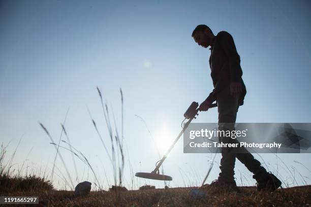 a young man using recreational metal detector to find treasure - treasure hunt stock pictures, royalty-free photos & images