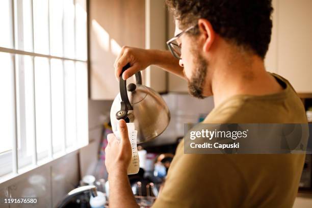 man preparing baby's bottle - baby bottle stock pictures, royalty-free photos & images