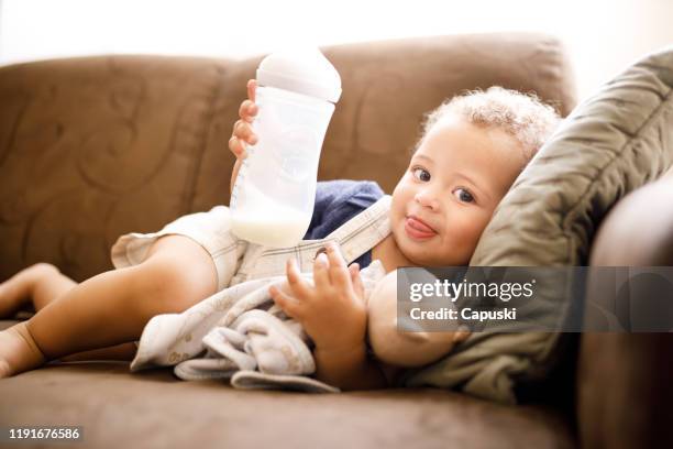 baby holding milk bottle - milk powder stock pictures, royalty-free photos & images