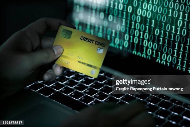 credit cards theft concept. hacker with credit cards on his laptop using them for unauthorized shopping - financial crime stock pictures, royalty-free photos & images