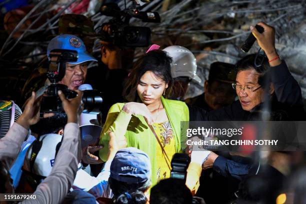 Cambodian Prime Minister Hun Sen speaks to a survivor after rescue workers pulled her from the rubbles of an under-construction building collapsed on...