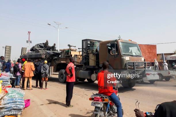 Pedestrians look on as a tank is transported on a truck in the streets of N'Djamena on January 3 upon their return after a months-long mission...