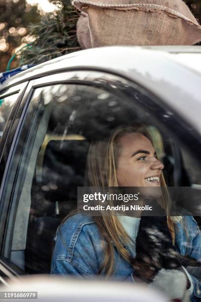 gelukkige vrouw zittend in een auto en glimlachend - christmas driving stockfoto's en -beelden