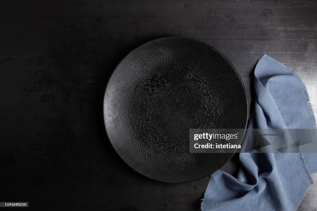 Empty rustic black concrete plate and linen napkin