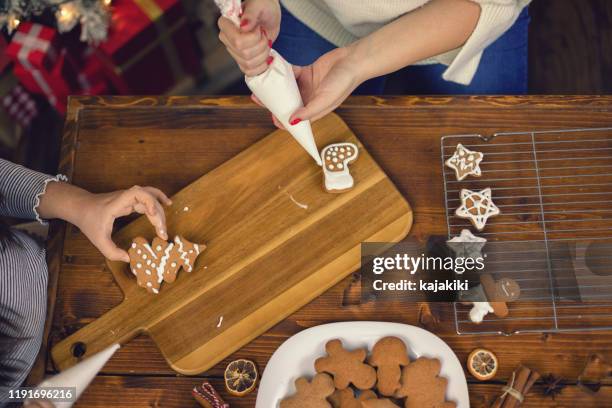 young family preparing christmas cookies at home - decorating a cake stock pictures, royalty-free photos & images