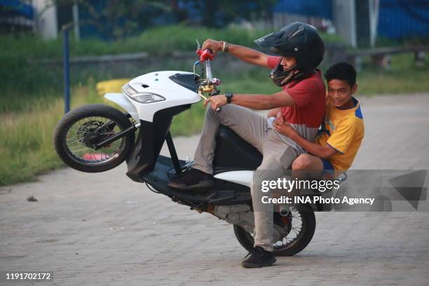 Teenager performs a Free Style action using a motorcycle in the parking area of ​​the Sumpah Pemuda Way Halim Stadium, Bandar Lampung, Indonesia,...