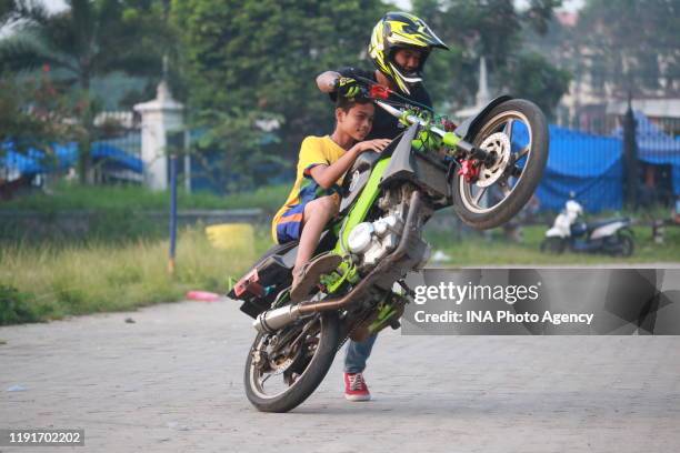 Teenager performs a Free Style action using a motorcycle in the parking area of ​​the Sumpah Pemuda Way Halim Stadium, Bandar Lampung, Indonesia,...