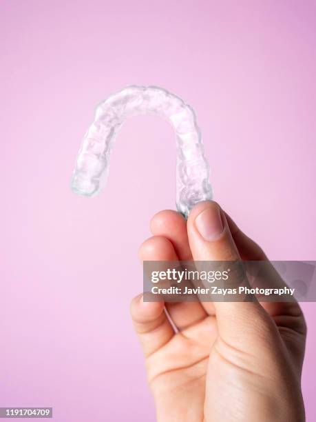 cropped hand holding transparent translucent invisible orthodontics - dental aligners stock pictures, royalty-free photos & images