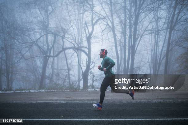 man running on the road. - winter running stock pictures, royalty-free photos & images
