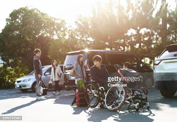 Young male in a wheelchair with his family preparing to play wheelchair tennis