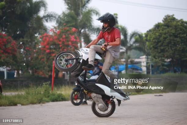 Teenager performs a Free Style action using a motorcycle in the parking area of ​​the Sumpah Pemuda Way Halim Stadium, Bandar Lampung, Indonesia,...