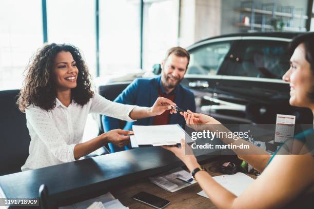 pareja en la sala de exposición comprando coche nuevo - auto nuevo fotografías e imágenes de stock