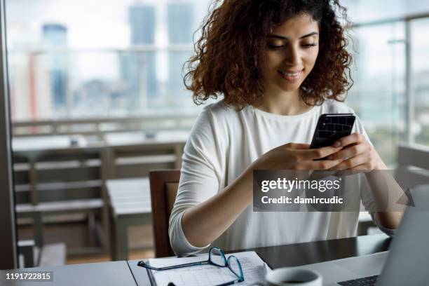 smiling young woman using mobile phone - school breakfast stock pictures, royalty-free photos & images