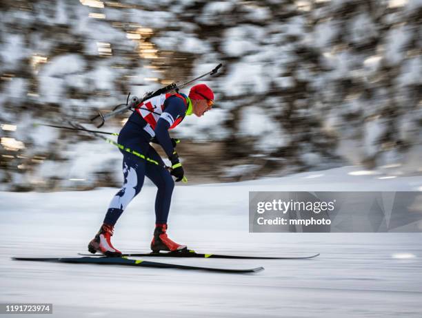 male biathlon competitor at cross-country skiing, motion blurred - biathlon ski stock pictures, royalty-free photos & images