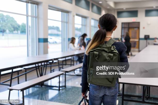 lonely middle school student in school cafeteria - sad girl standing stock pictures, royalty-free photos & images