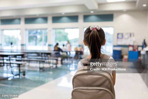 rear view of young schoolgirl entering cafeteria - loneliness stock pictures, royalty-free photos & images