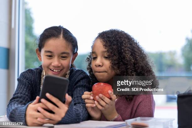 les amies de l'école intermédiaire utilisent le téléphone intelligent pour le selfie - kids play apple photos et images de collection
