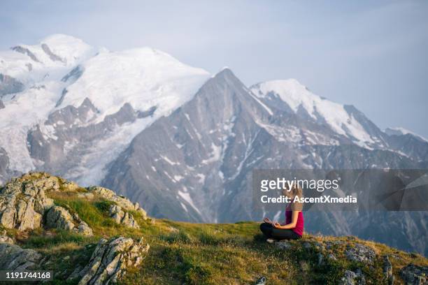 weibliche yogi meditiert auf bergrücken - yoga in the snow stock-fotos und bilder