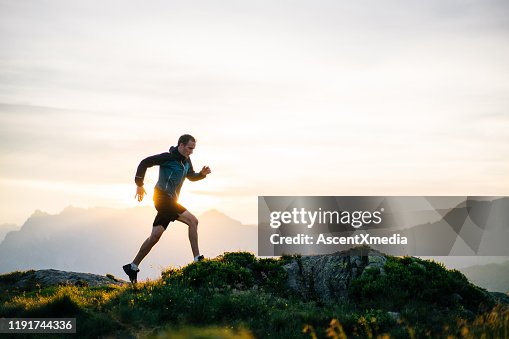 Jonge man loopt op bergkam bij zonsopgang Jonge man loopt op bergkam bij zonsopgang