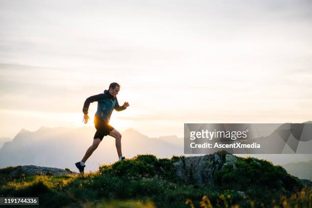 young man runs on mountain ridge at sunrise - jogging stock pictures, royalty-free photos & images