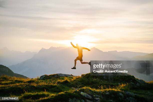 young man runs on mountain ridge at sunrise - leap forward stock pictures, royalty-free photos & images