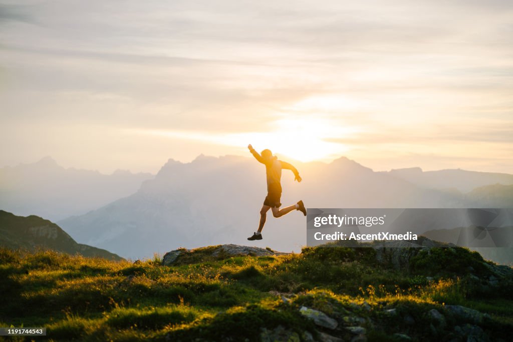 Junger Mann rennt bei Sonnenaufgang auf Bergrücken