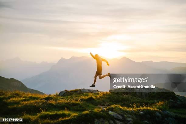 joven corre en la cresta de la montaña al amanecer - people jumping fotografías e imágenes de stock