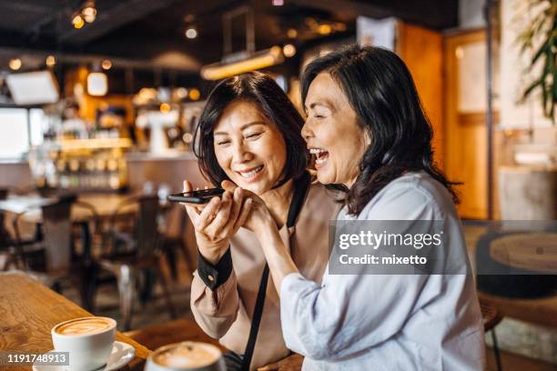 seniorinnen senden sprachnachricht am telefon im restaurant - speech recognition stock-fotos und bilder