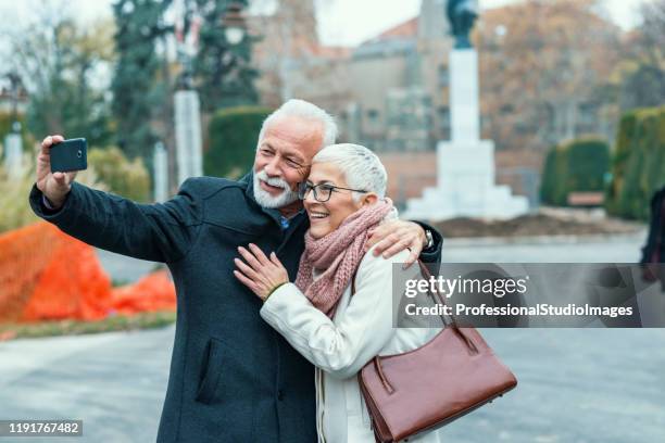 senior couple is photographing themselves in the city streets - old couple restaurant stock pictures, royalty-free photos & images