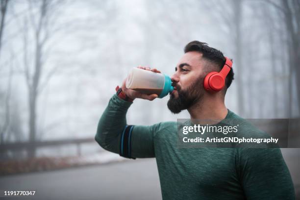 man drinking energy drink after exercising. - protein drink stock pictures, royalty-free photos & images