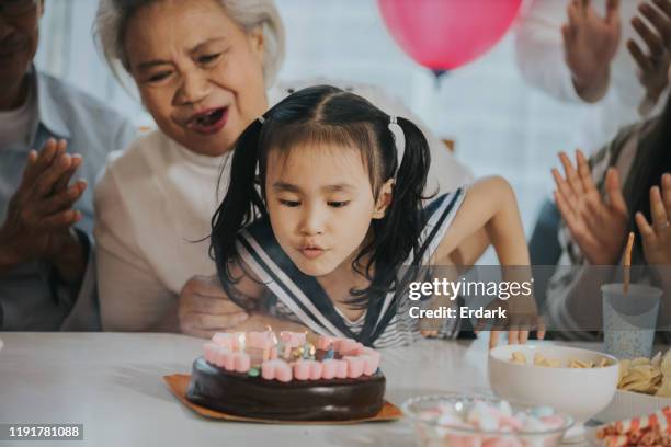 famiglia che festeggia il compleanno della ragazza a casa foto d'archivio - parents children blow candles asians foto e immagini stock