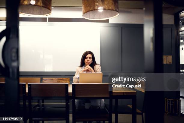 woman working late at the office - working late imagens e fotografias de stock