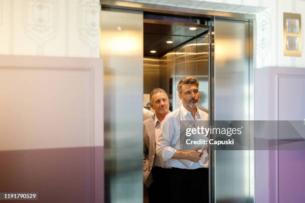 zakenman uitstappen uit de lift - lift stockfoto's en -beelden